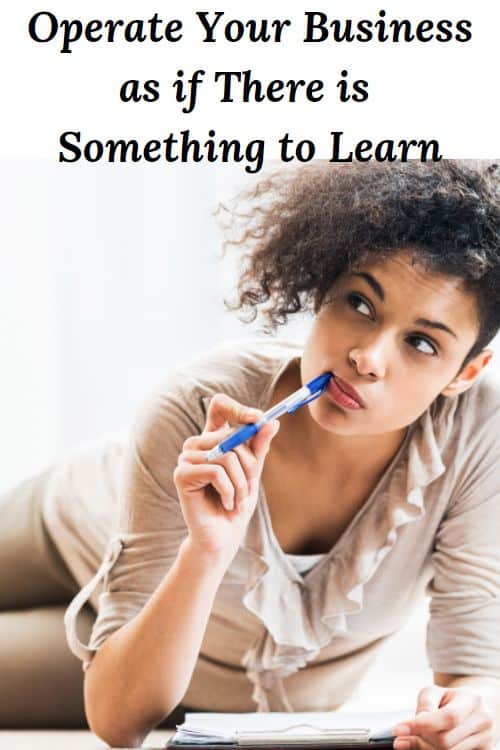 African American woman laying down chewing on a pen with a notebook and the words "Operate Your Business as if There is Something to Learn"