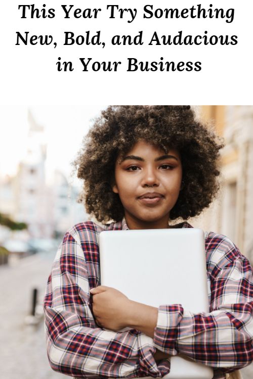 African American woman smiling holding a laptop and the words "This Year Try Something New Bold and Audacious in Your Business"